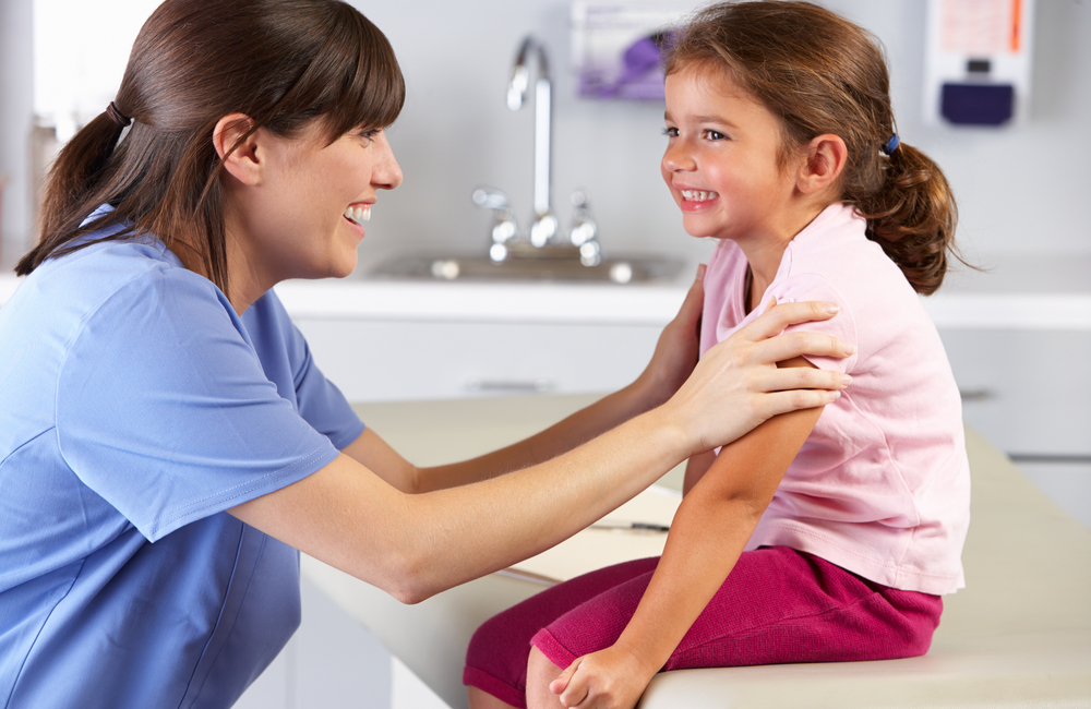 A pediatric nurse practitioner helps a child patient relax before an exam.