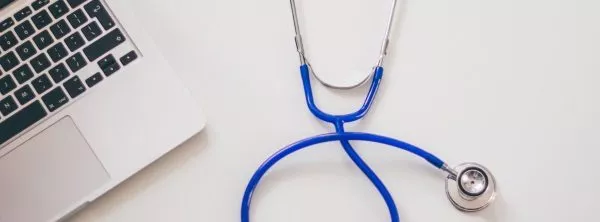 A stethoscope lies beside an open laptop.