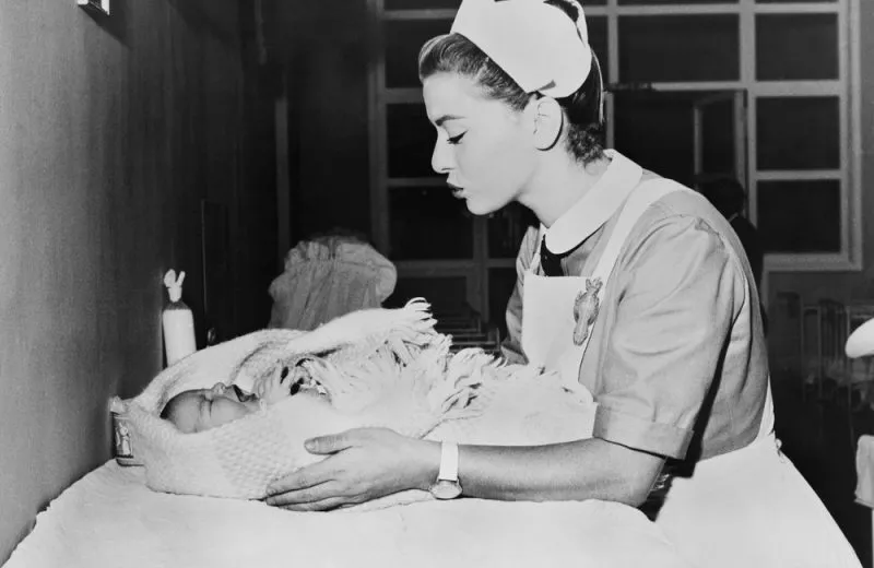 A black and white photo of a nurse soothing an infant.