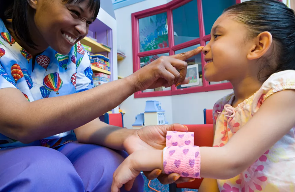 A nurse practitioner smiles at a young patient.