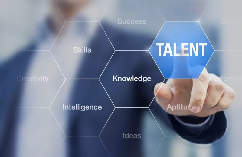 A hand in the background reaches toward a transparent screen with words like "Knowledge" and "Intelligence" and presses on the section labeled "Talent."