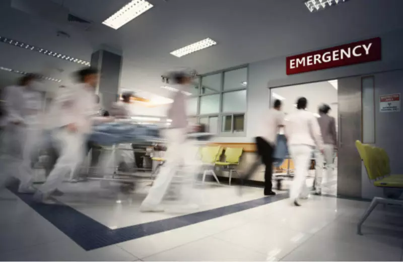 A blur of nurses roll a patient into an emergency room.