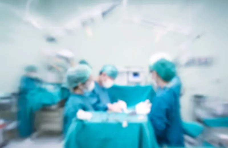 A group of nurses surround a patient in an emergency room.