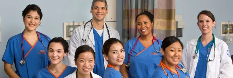 A diverse group of nurses in scrubs smile at the camera.