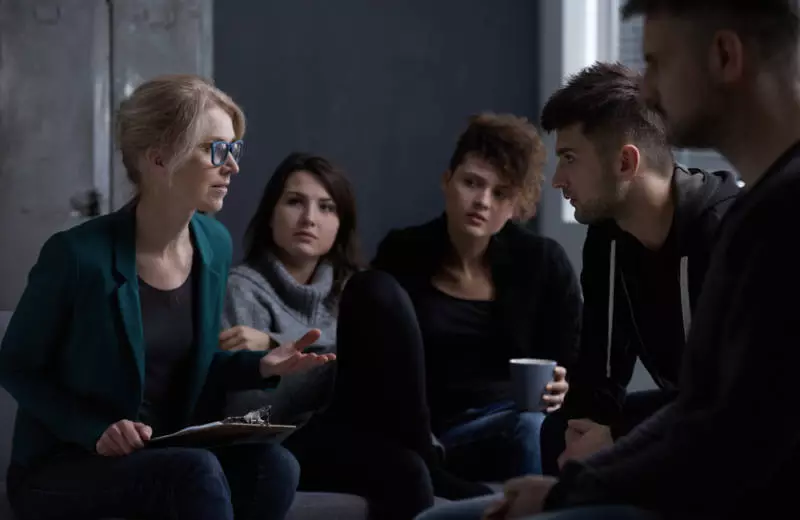 A nurse practitioner speaks to a group of young adults.