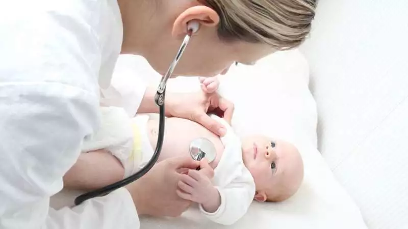 A pediatric nurse practitioner uses a stethoscope to listen to an infant's heartbeat.