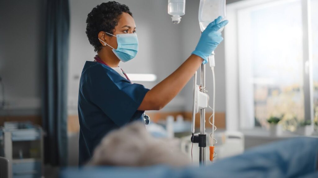 A nurse administers an IV to a hospital patient.